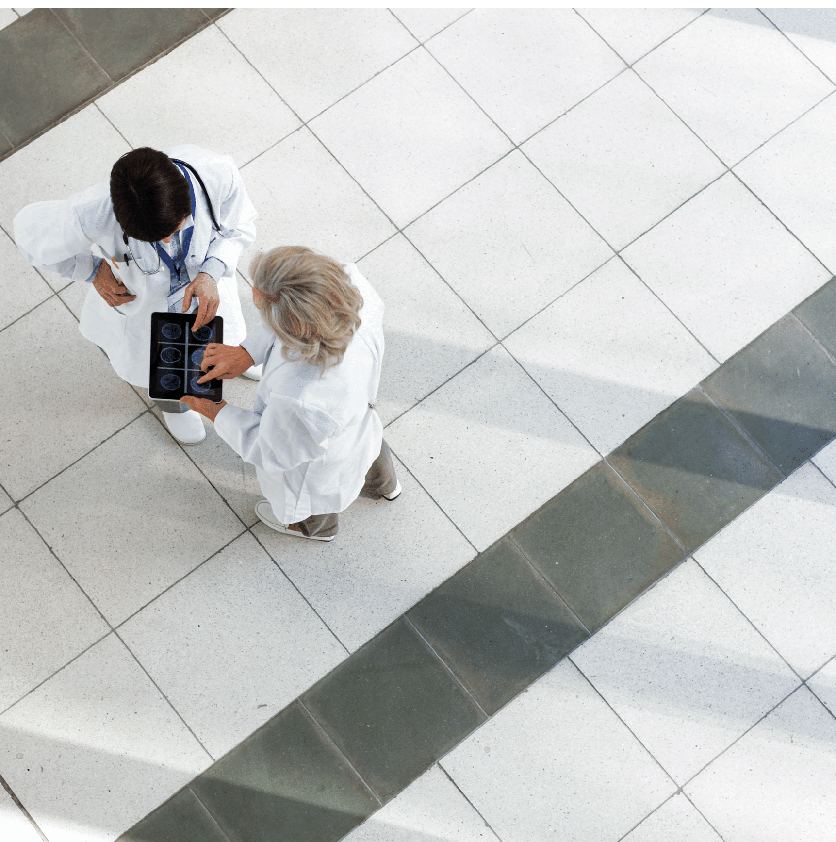 Hospital staff discussing patient care. The Doctors are using a digital tablet with the patient's chart.