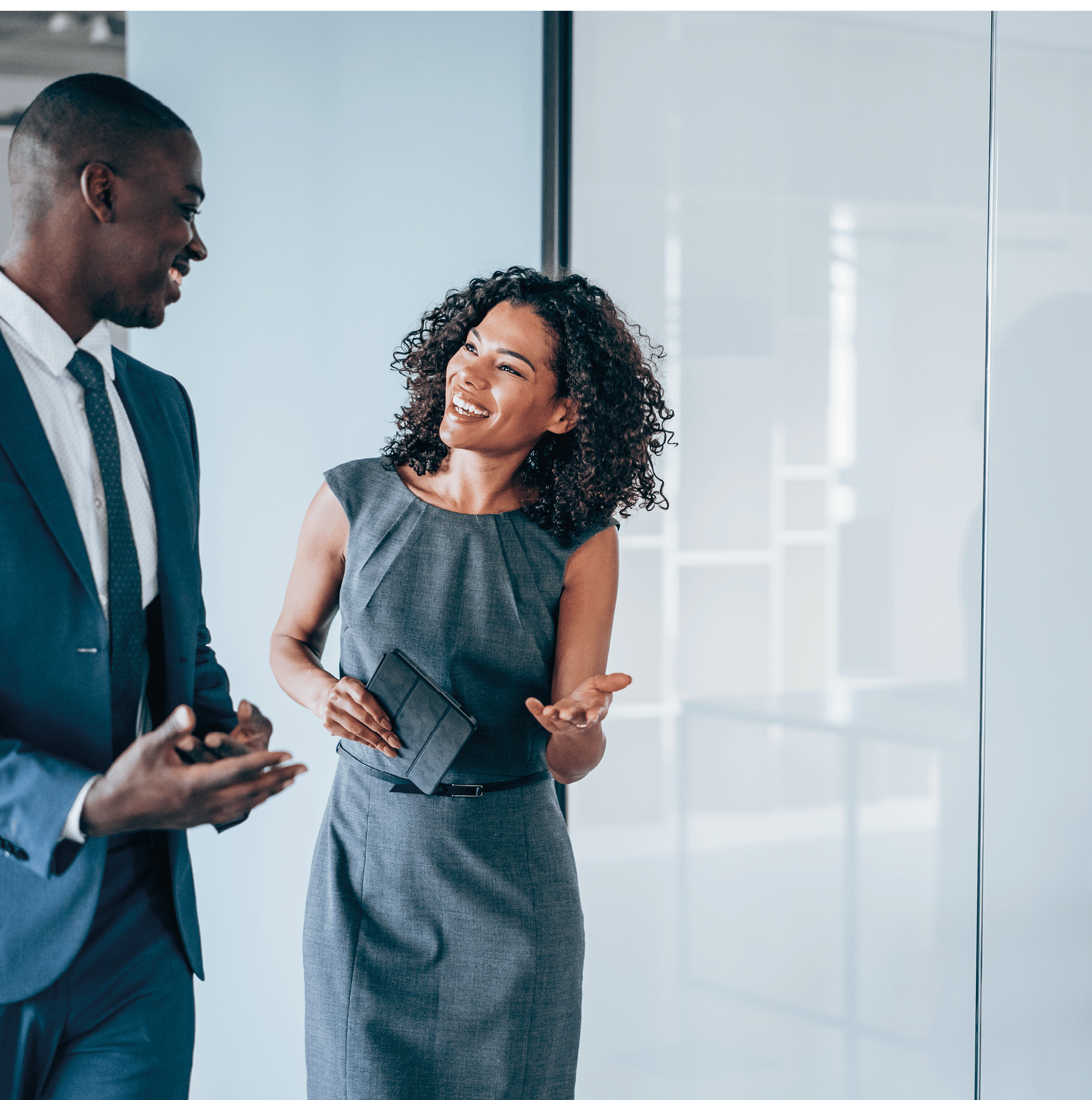 Shot of two young colleagues having a discussion in modern office. Confident young business people working together in the office. Corporate business persons discussing new project and sharing ideas in the workplace.