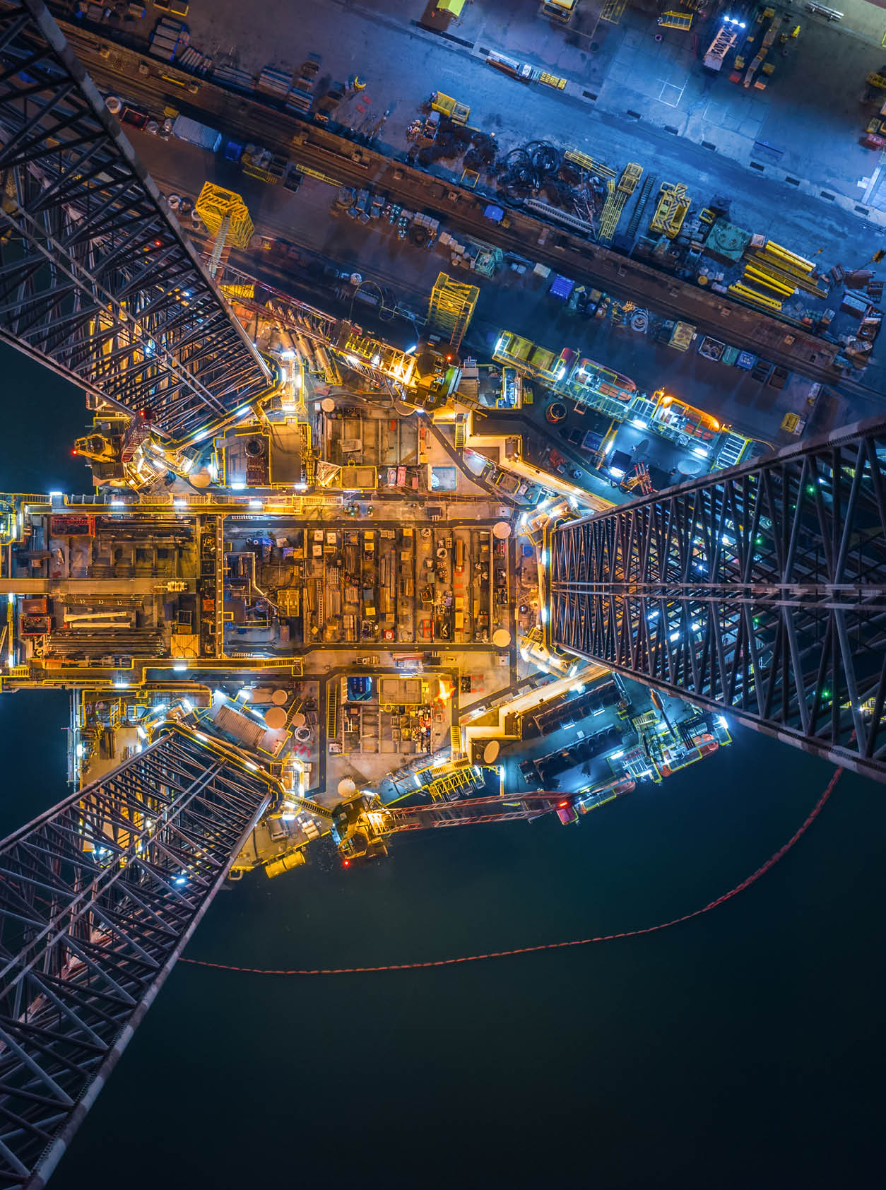 World at work drone view of Oil and gas jack-up rig at the yard for maintenance with many vessels, the petroleum rig is applied for producing oil and gas in offshore in the petroleum industry.